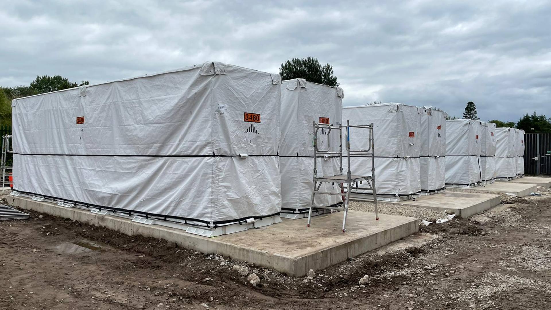 Containerized BESS cost benchmark: grid-scale battery containers installed on concrete pads at a storage site