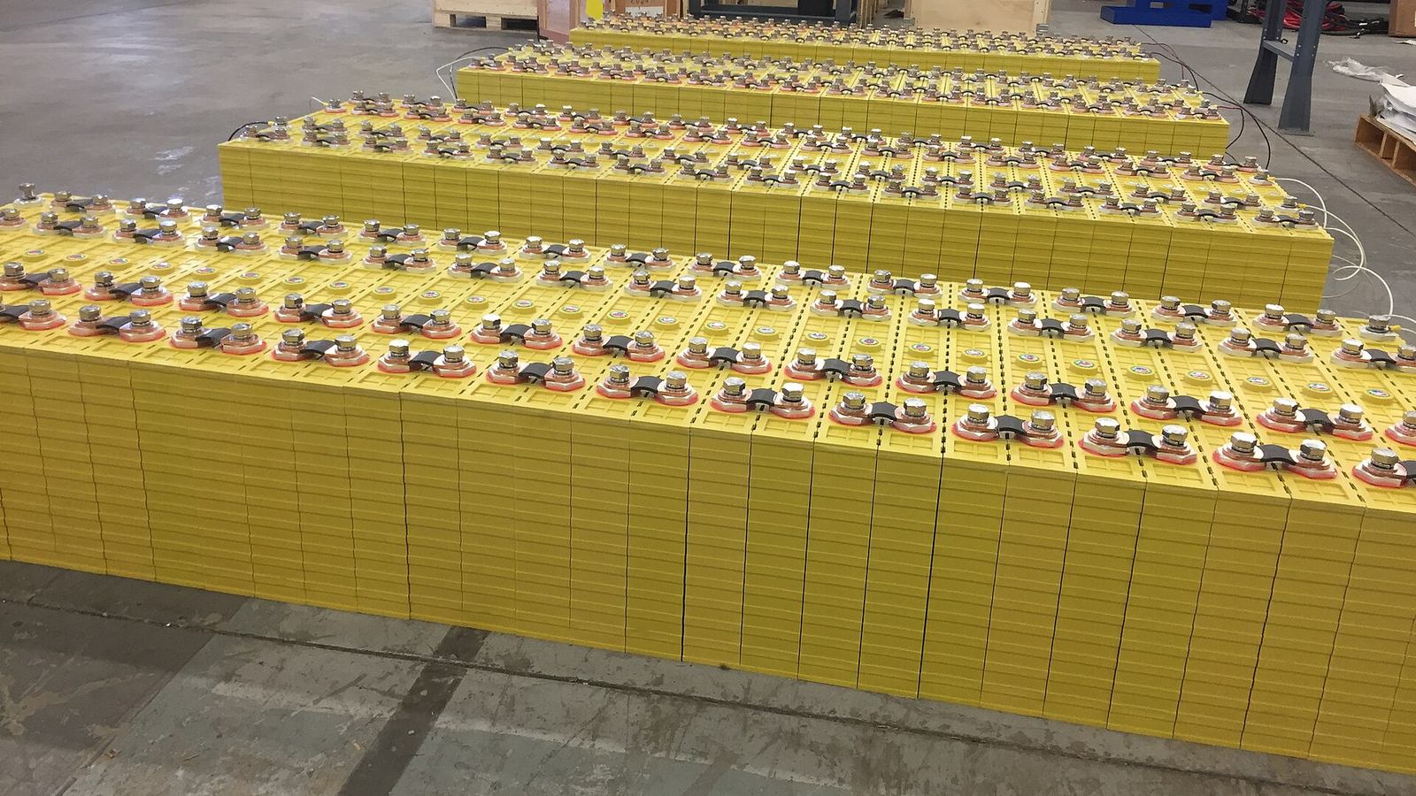 Rows of 700 Ah lithium iron phosphate cells staged in a warehouse before they are built into storage racks